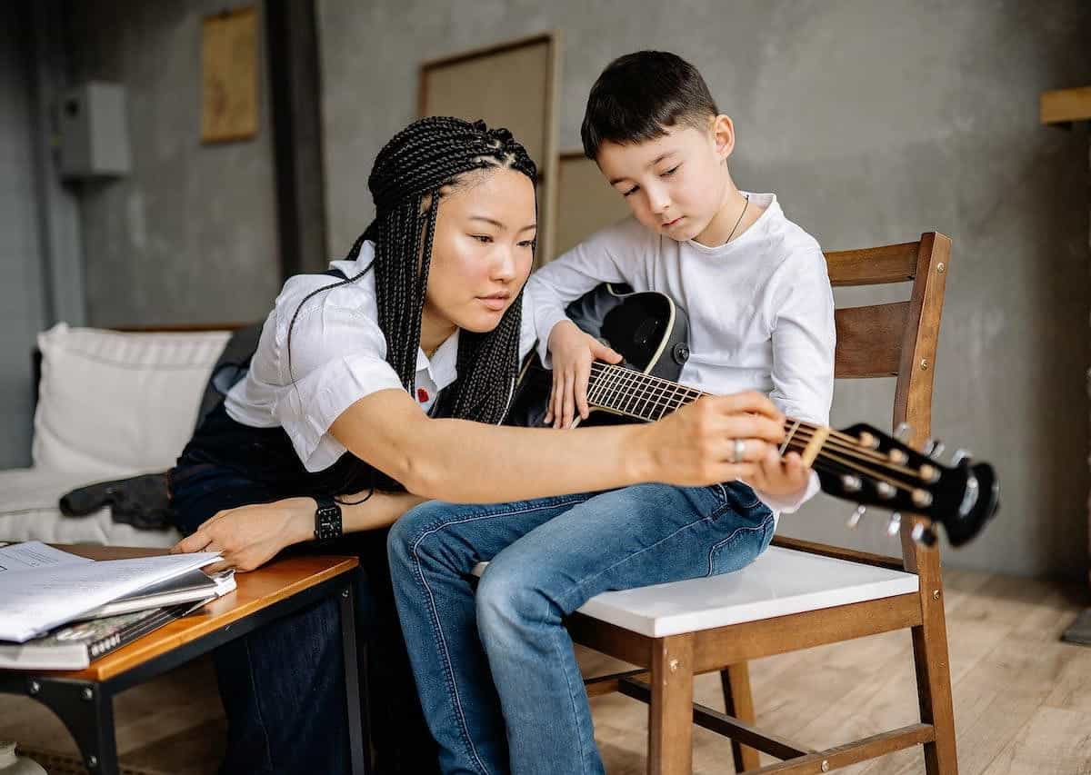 women teaching boy how to play guitar, one of the best side jobs for stay-at-home moms